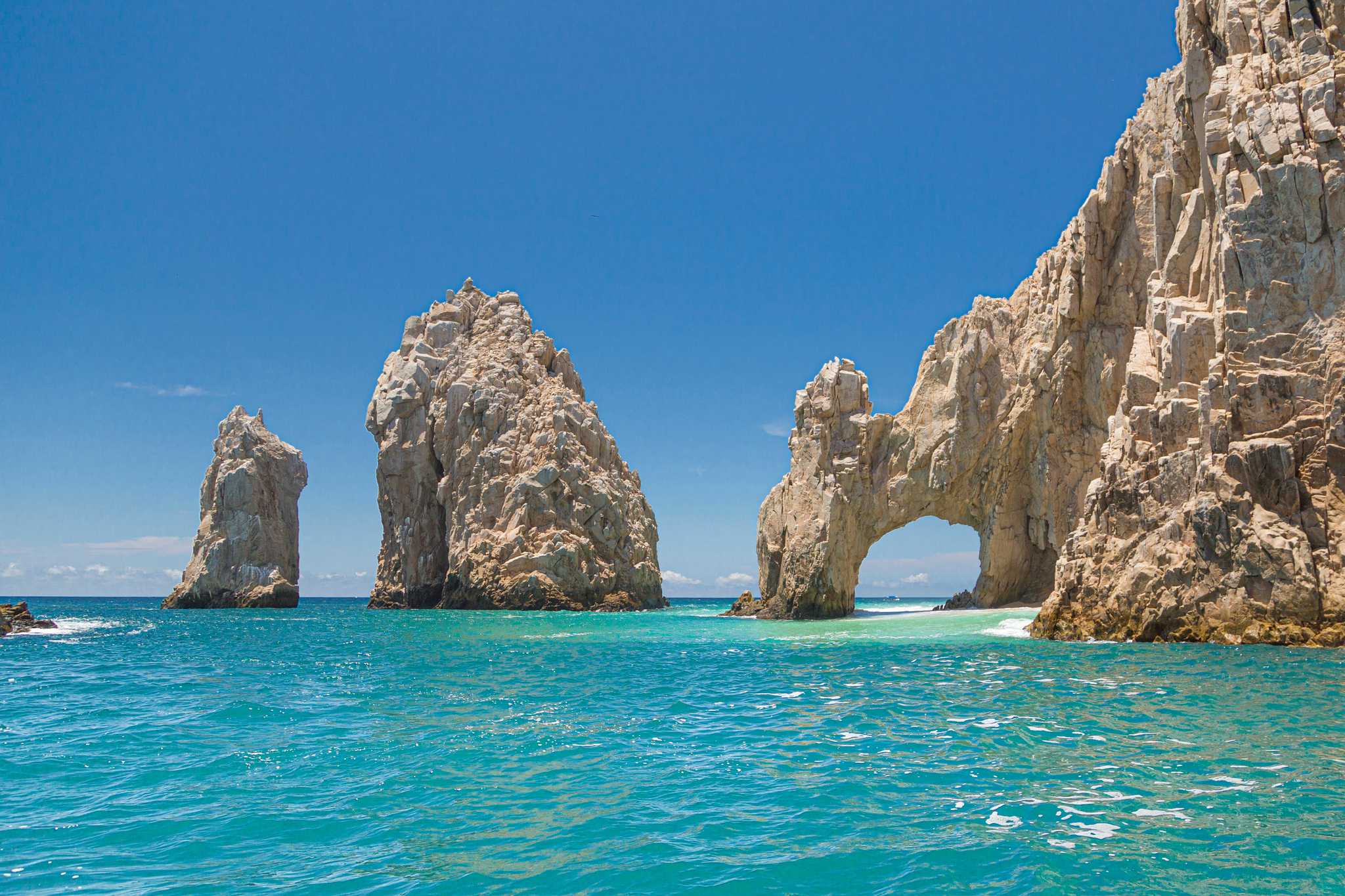The Los Cabos arch, a natural white stone arch in the sea beside other rock formations.