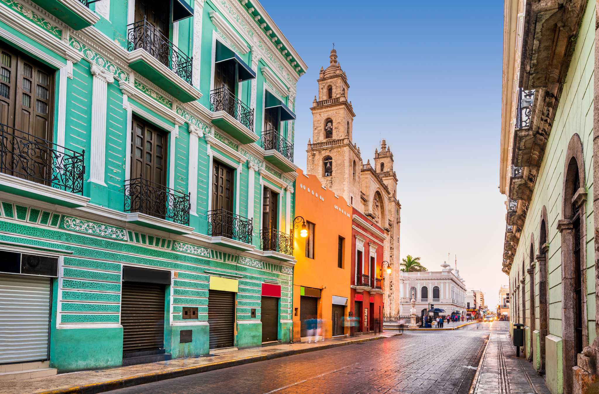 Colorful buildings and colonial church tower on a street in MĂŠrida, Mexico.