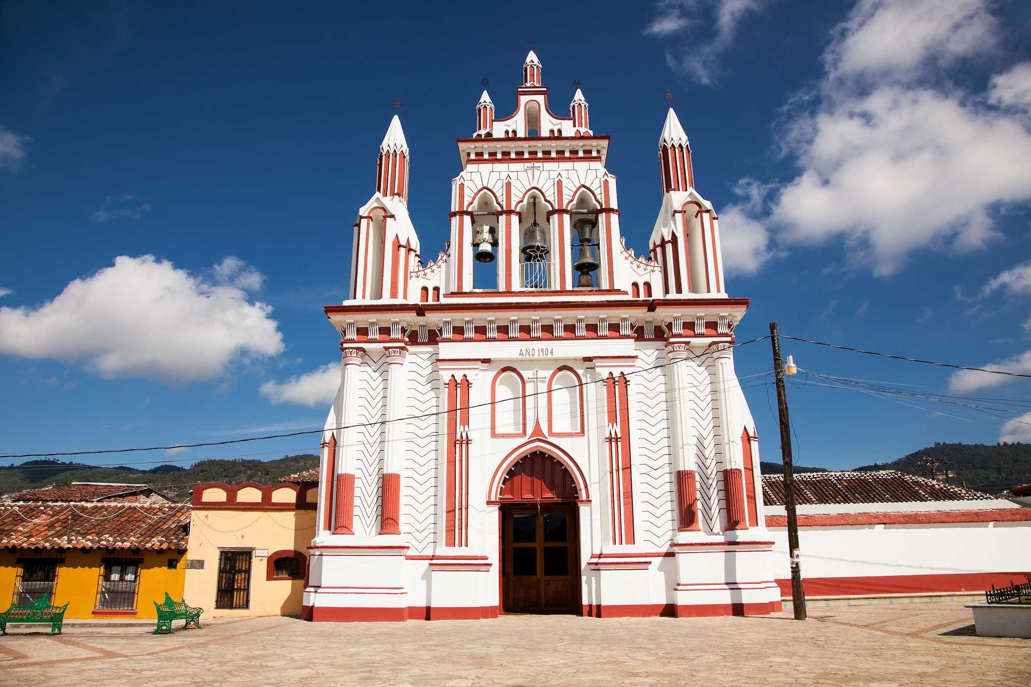 White and red detailed church facade with bells in San Cristobal de las Casas.