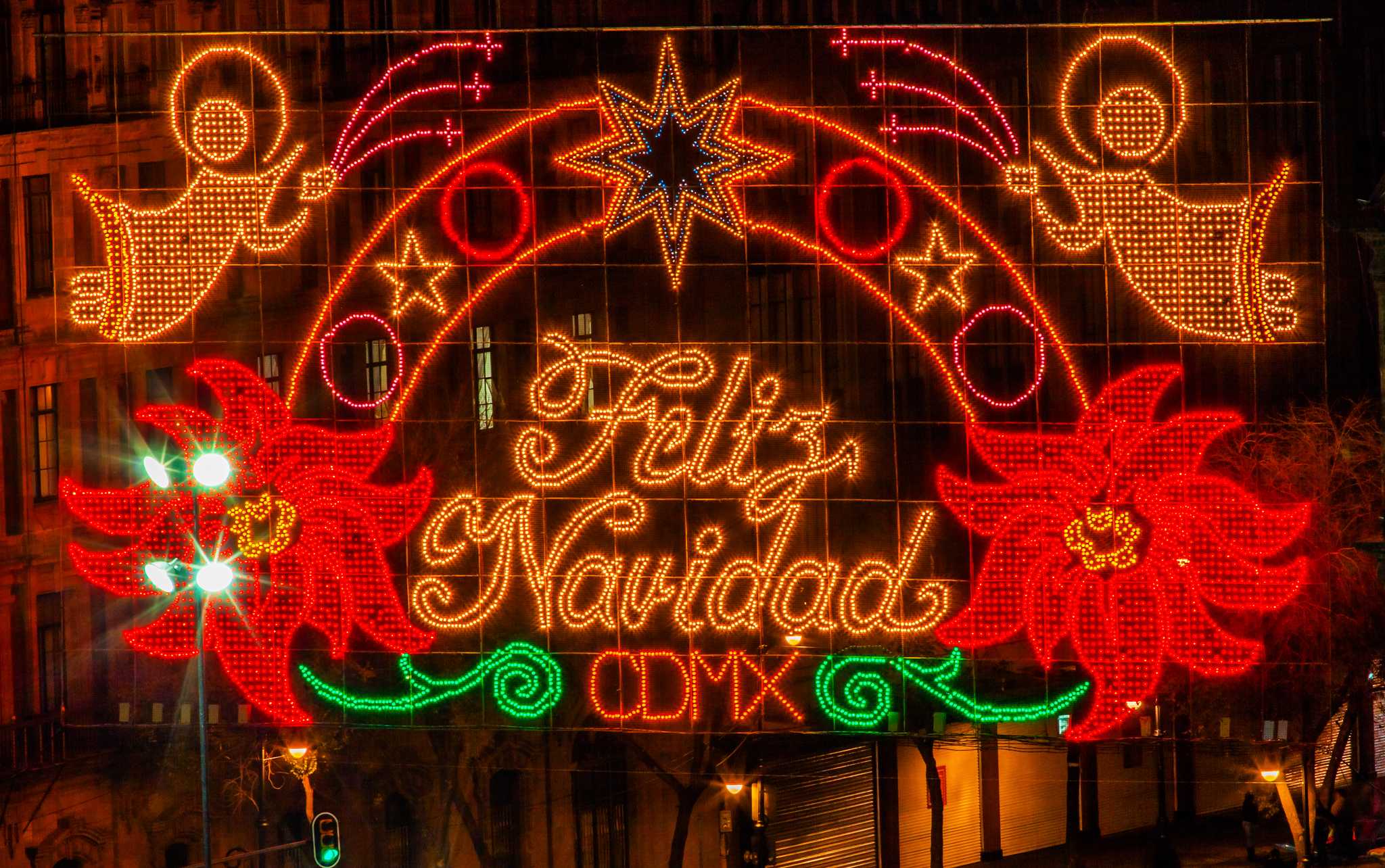 Feliz Navidad light display with angels and poinsettias on a building in Mexico City.
