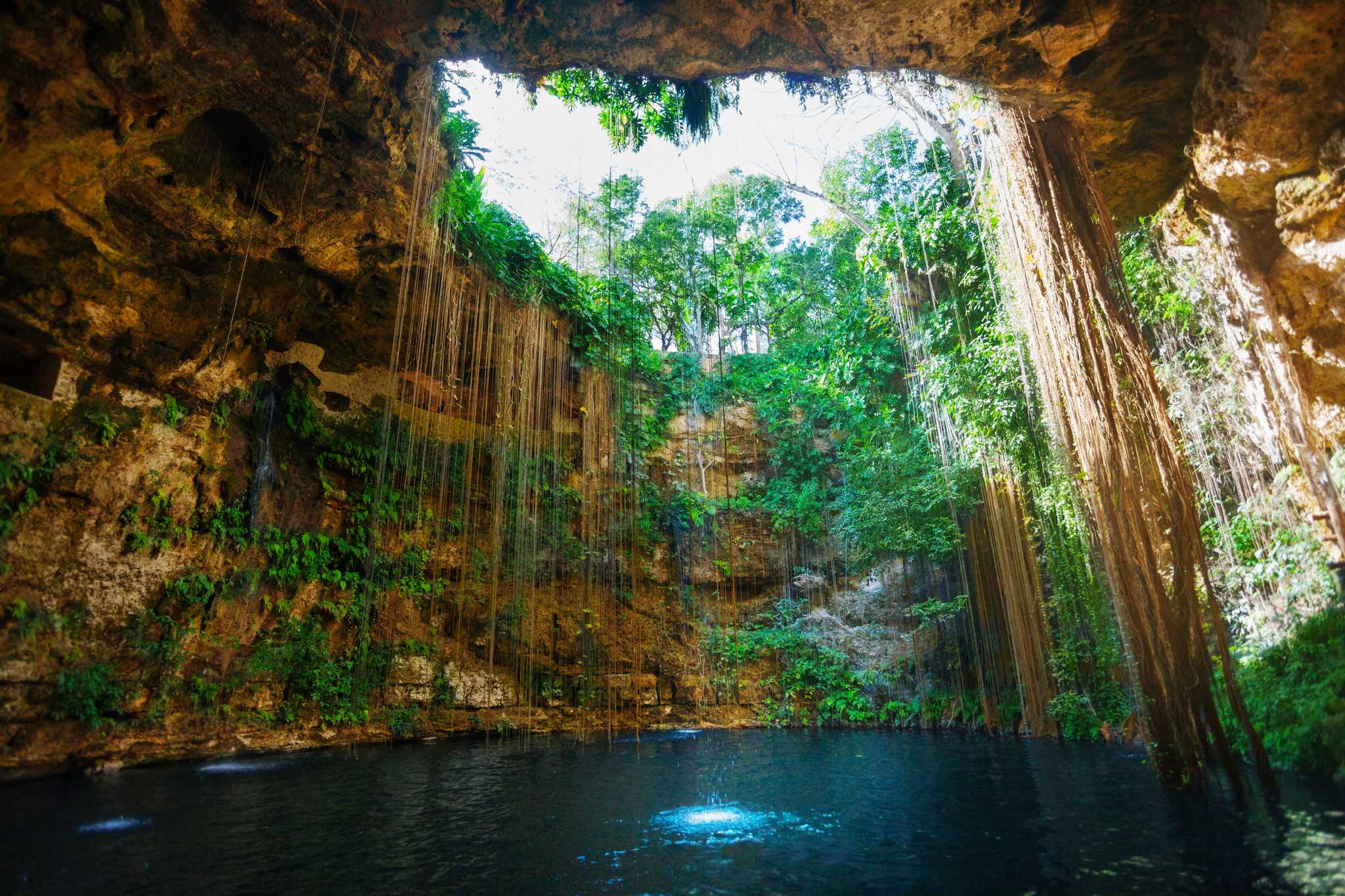 Sunbeams filtering from cave opening into Ik Kil cenote in Mexico.