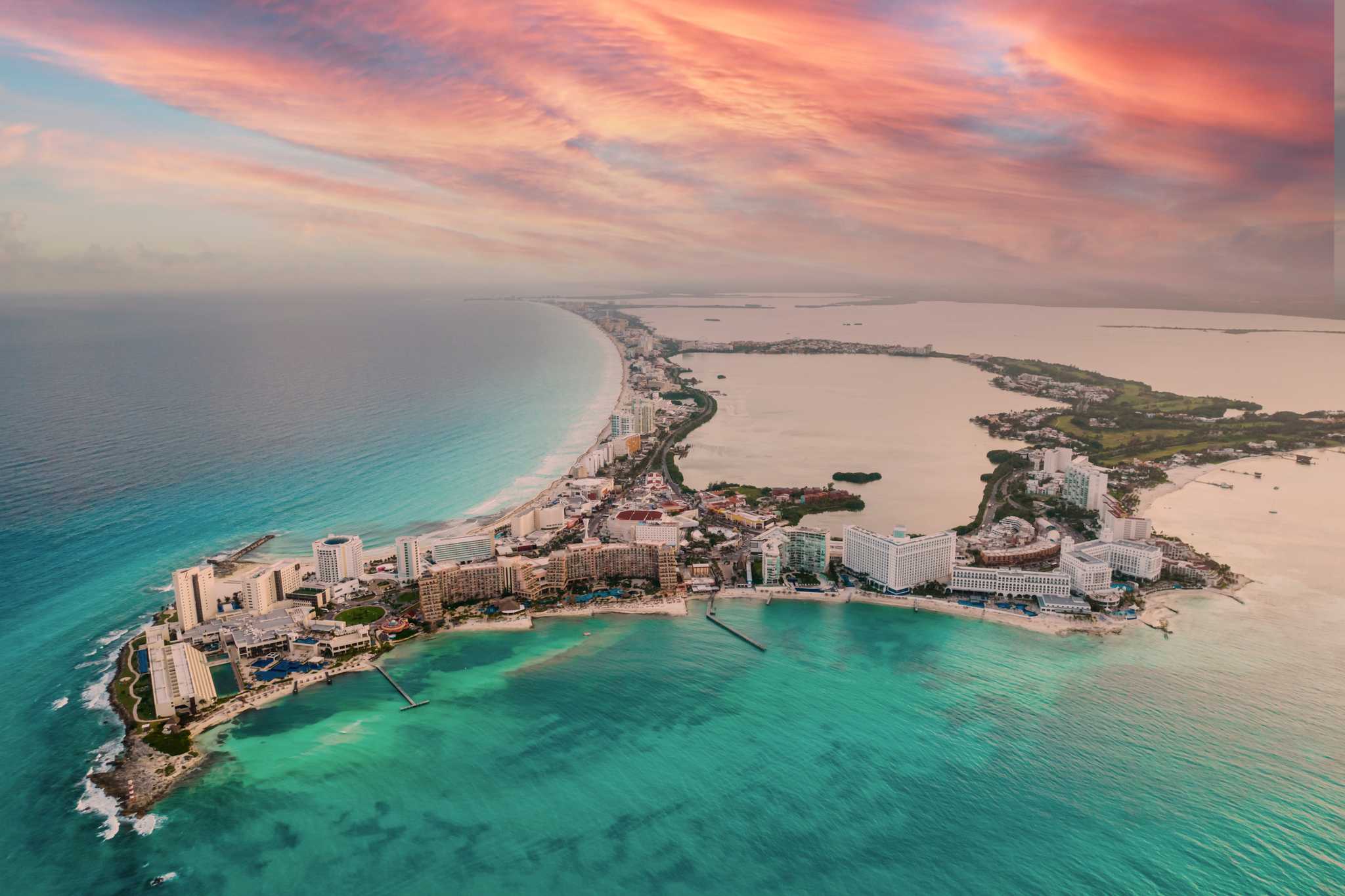 Pink sunset over the coastline of Cancún in Quintana Roo, reflecting in turquoise water.