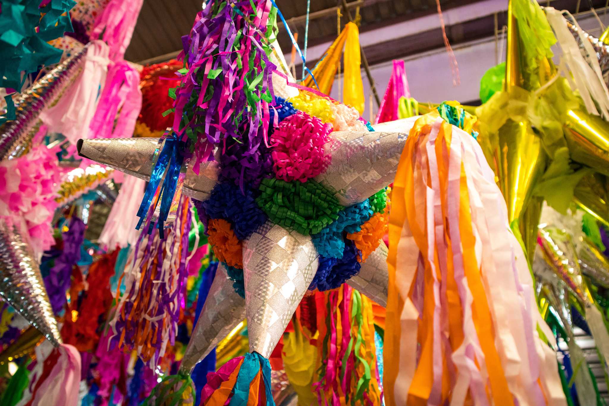 Close-up of a rainbow-colored piñata with streamers at a market in Mexico.