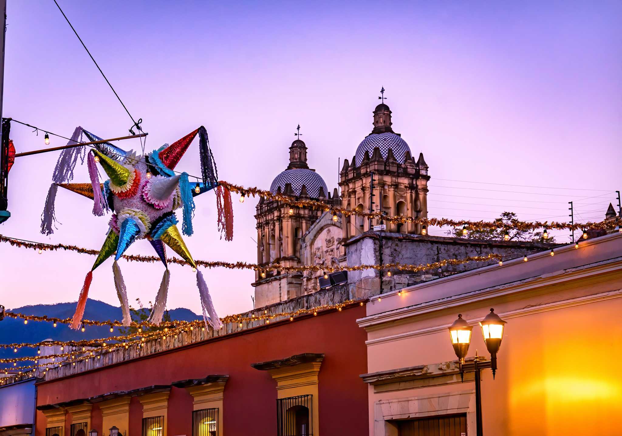 Sunset over Santa Domingo Guzman in Oaxaca, Mexico, with a piñata in front.