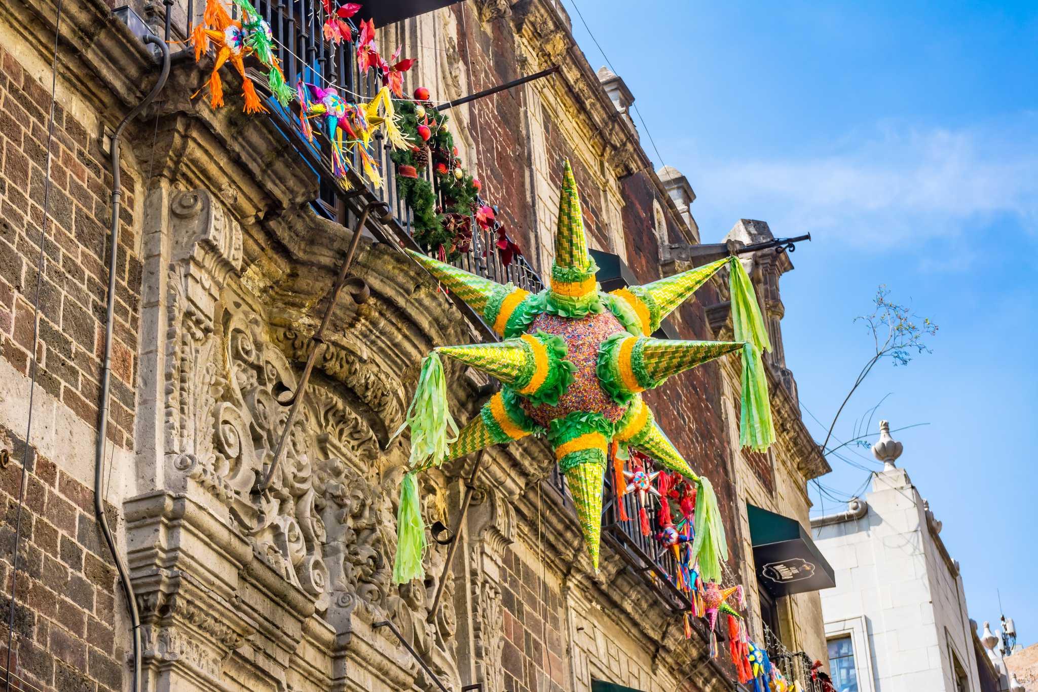 Close up of green and yellow seven-pointed star pinata on a building in Mexico City.
