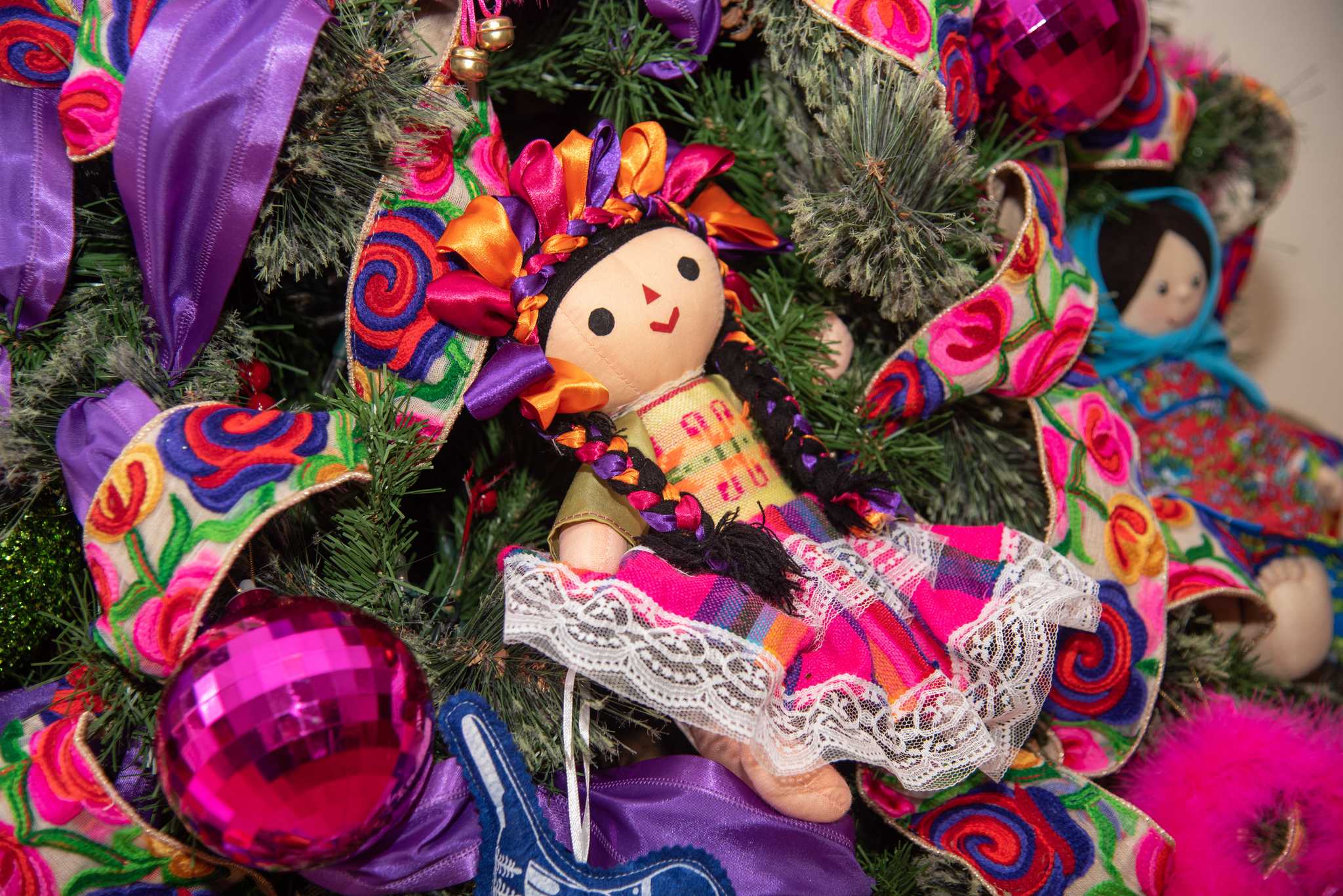 Pink and purple decorated Christmas tree branch with traditional rag doll, in Mexico.