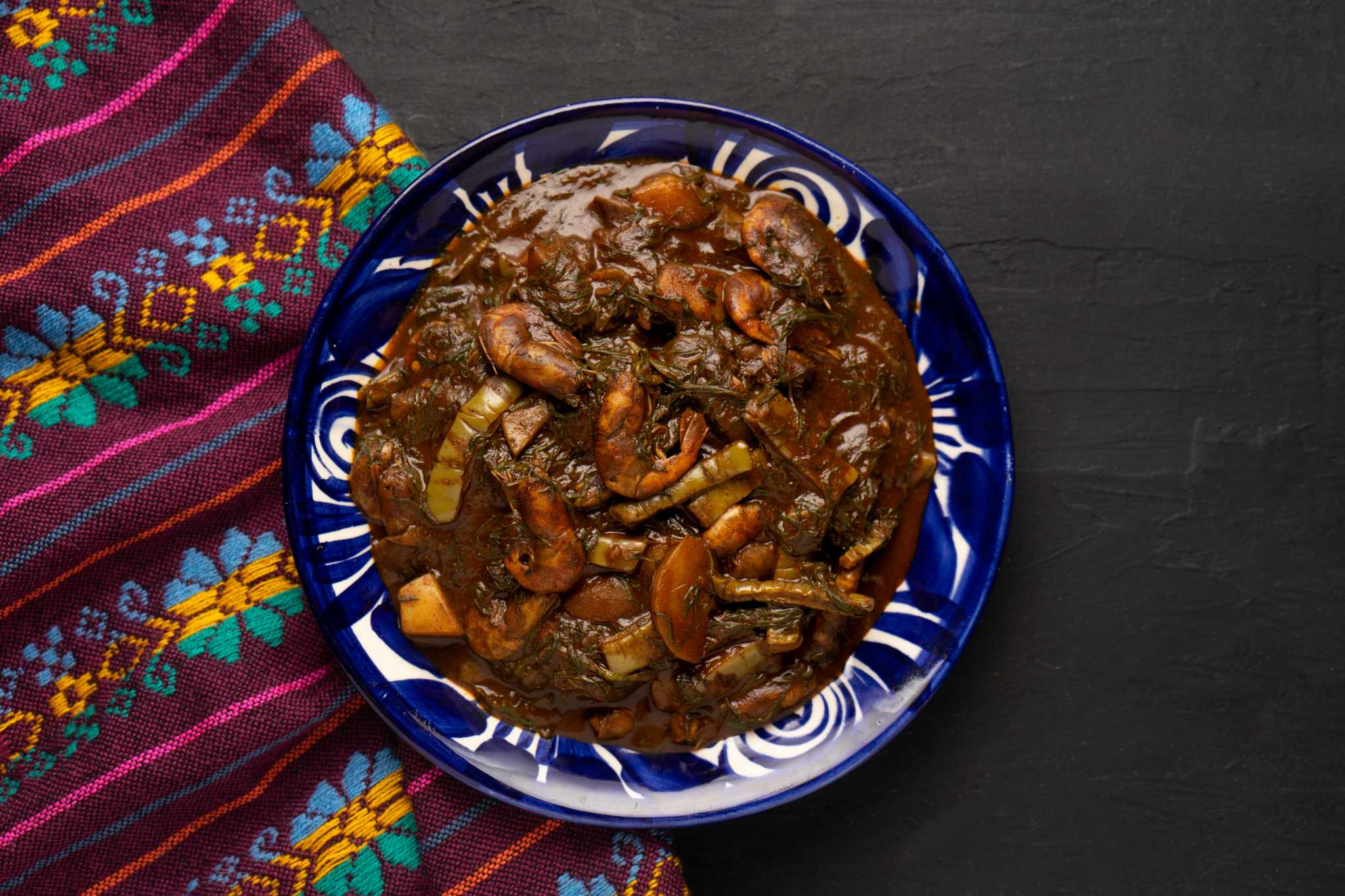 Mexican Romertiros with shrimp in a blue and white dish beside a purple embroidered cloth.