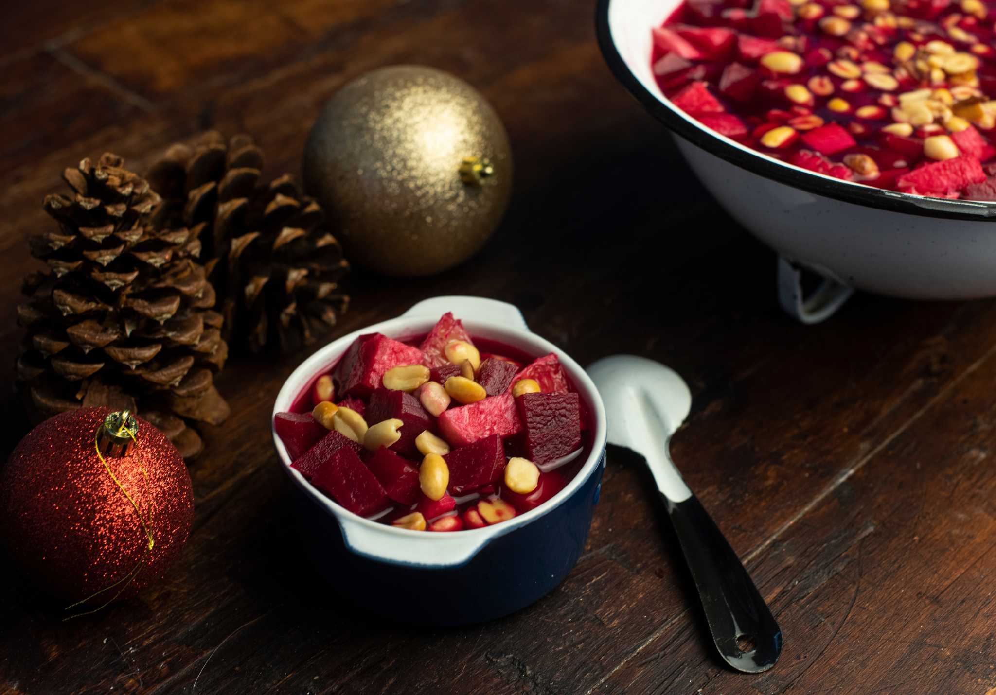 Small dish of Ensalada de Nochebuena with beets and peanuts, beside Christmas ornaments.