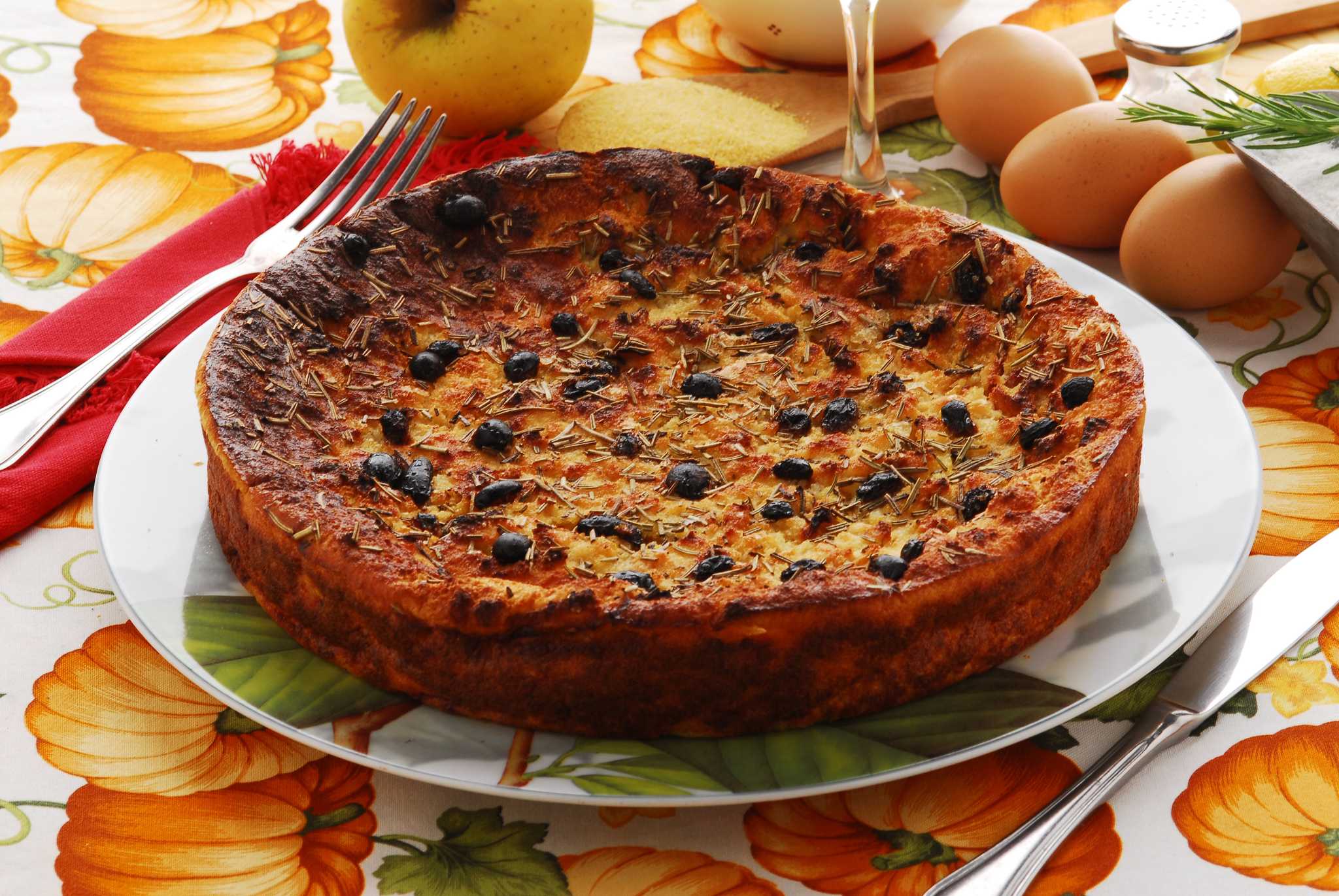 A round golden baked cake studded with raisins and sprinkled with rosemary.