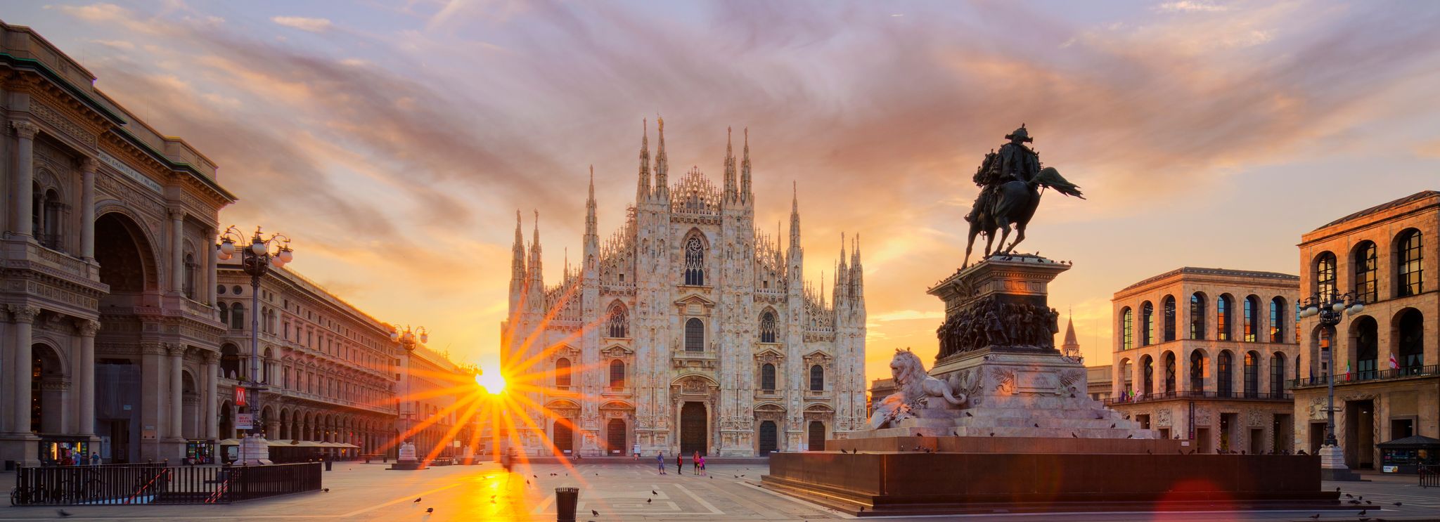 Milan’s famous Duomo, a large, white stone cathedral, at sunset on Piazza del Duomo