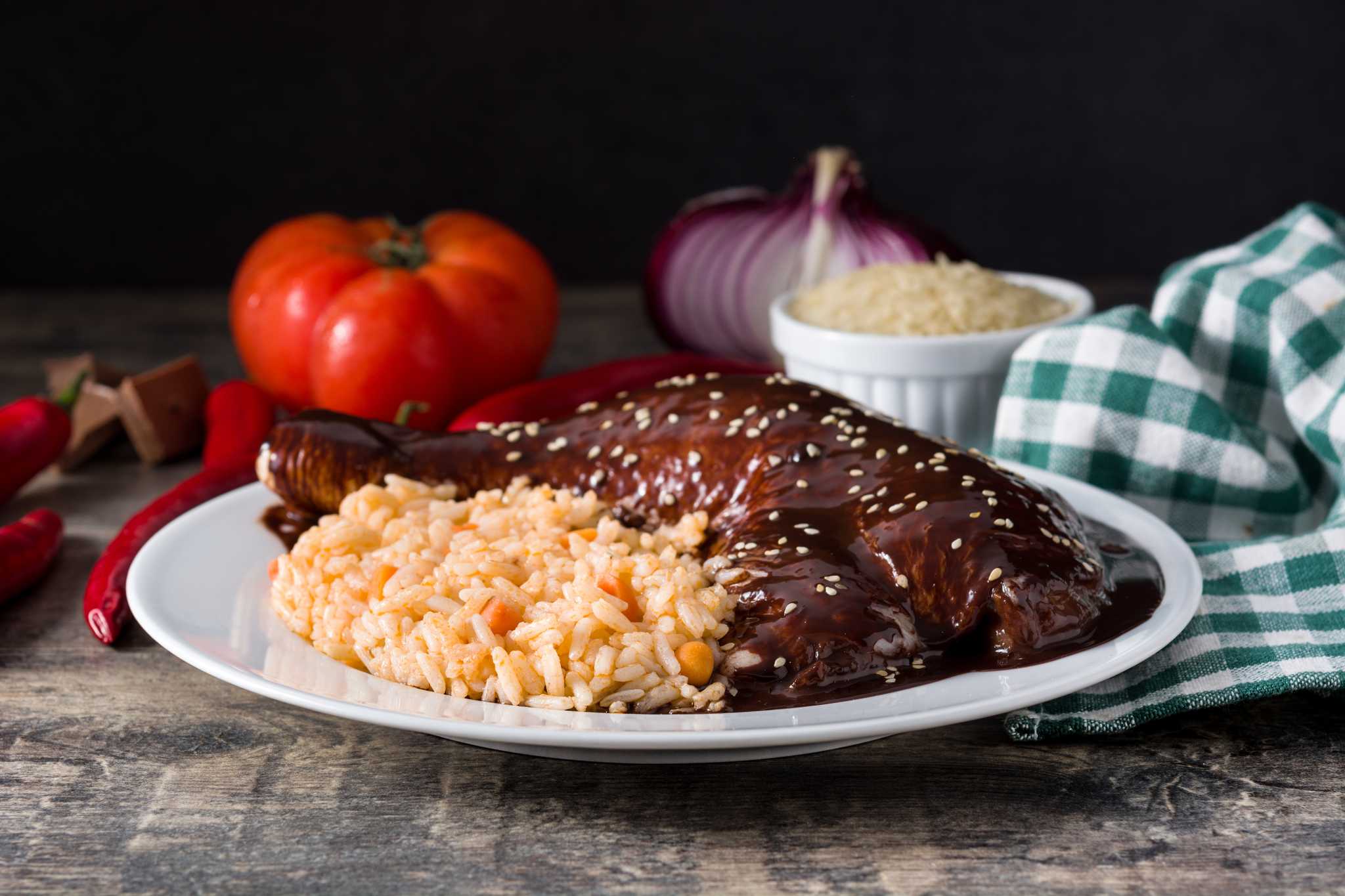 Rice and chicken topped with a dark brown mole poblano sauce and seeds.
