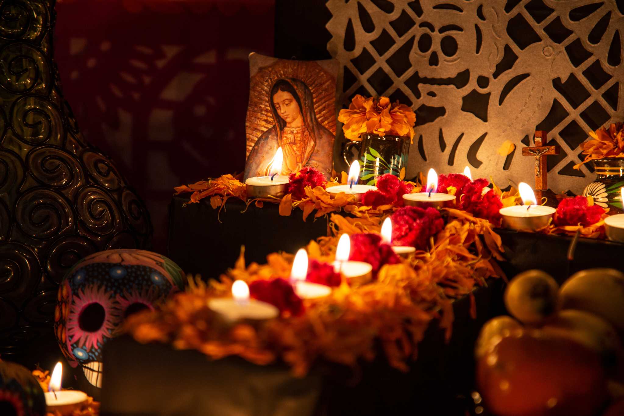 Ofrenda with a Virgin of Guadalupe image, candles, marigolds, and papel picado.