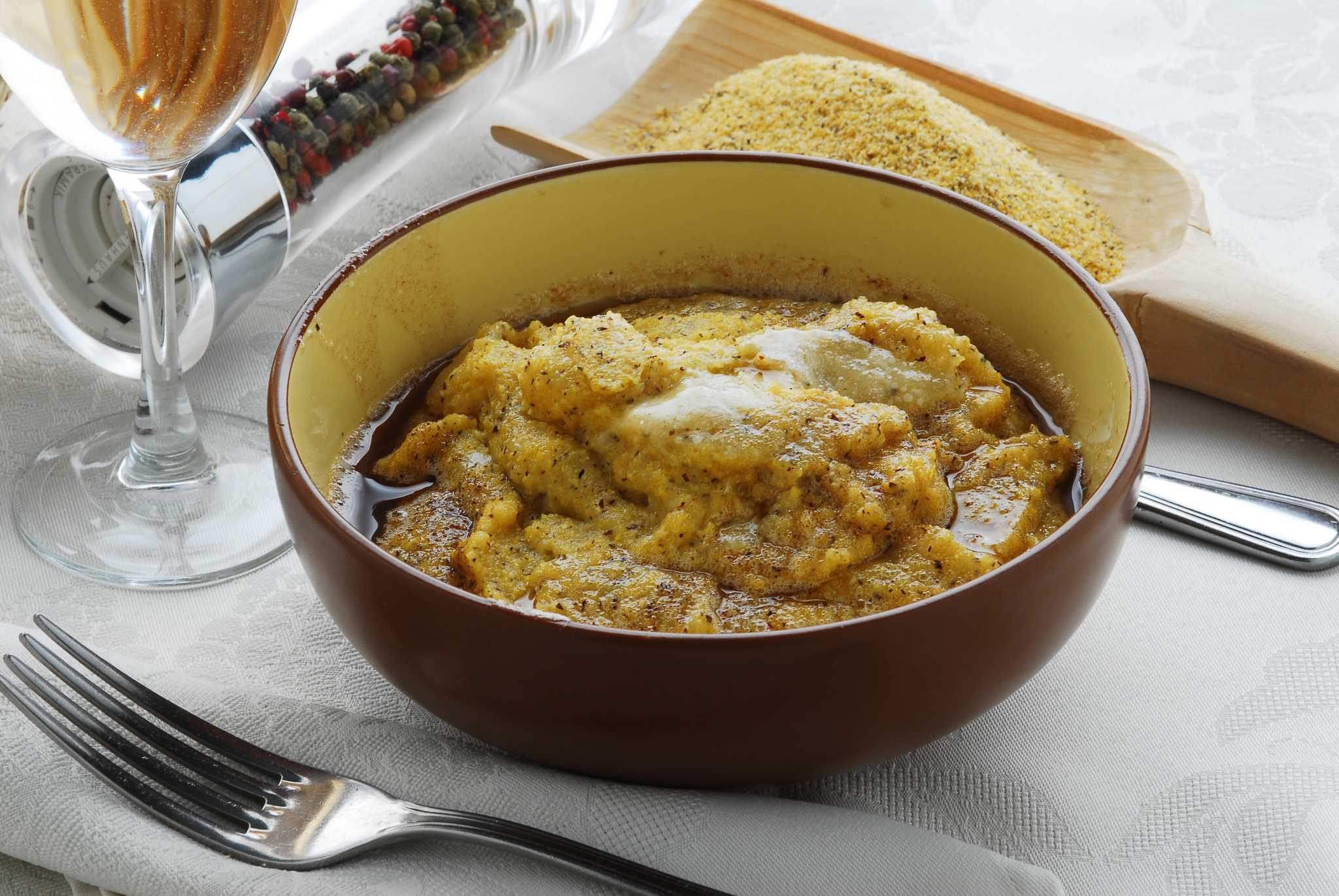 A rustic bowl of polenta topped with melted cheese and browned butter.