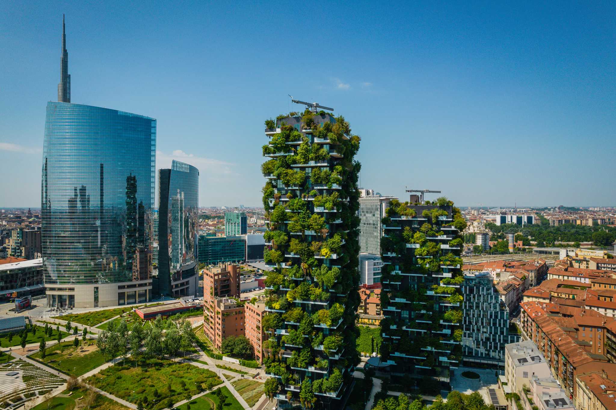 Sleek skyscrapers rise above Milan, with the Vertical Forest building at the center.