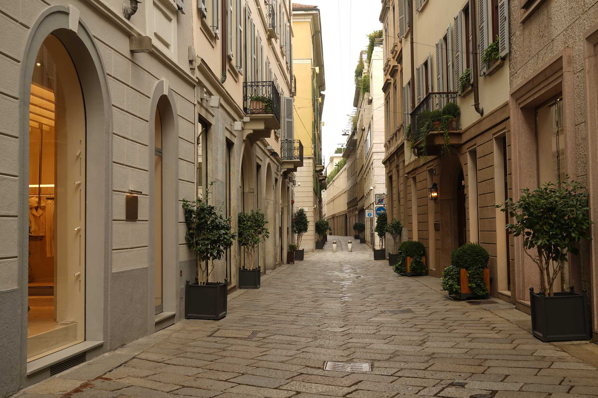 A cobblestone street lined with upscale fashion boutiques and balconies.