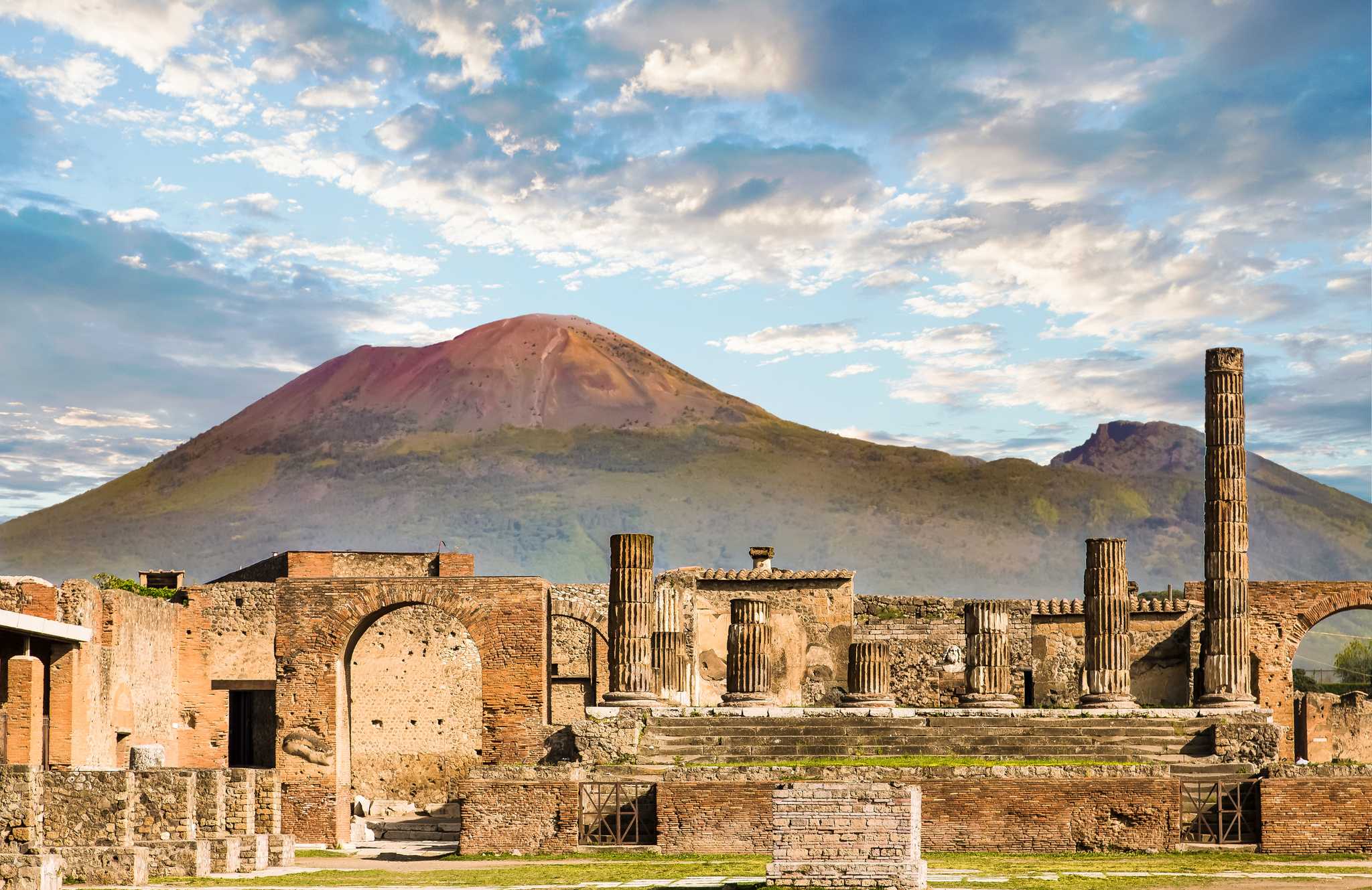 A close shot of the Pompeii ruins with Mount Vesuvius behind.