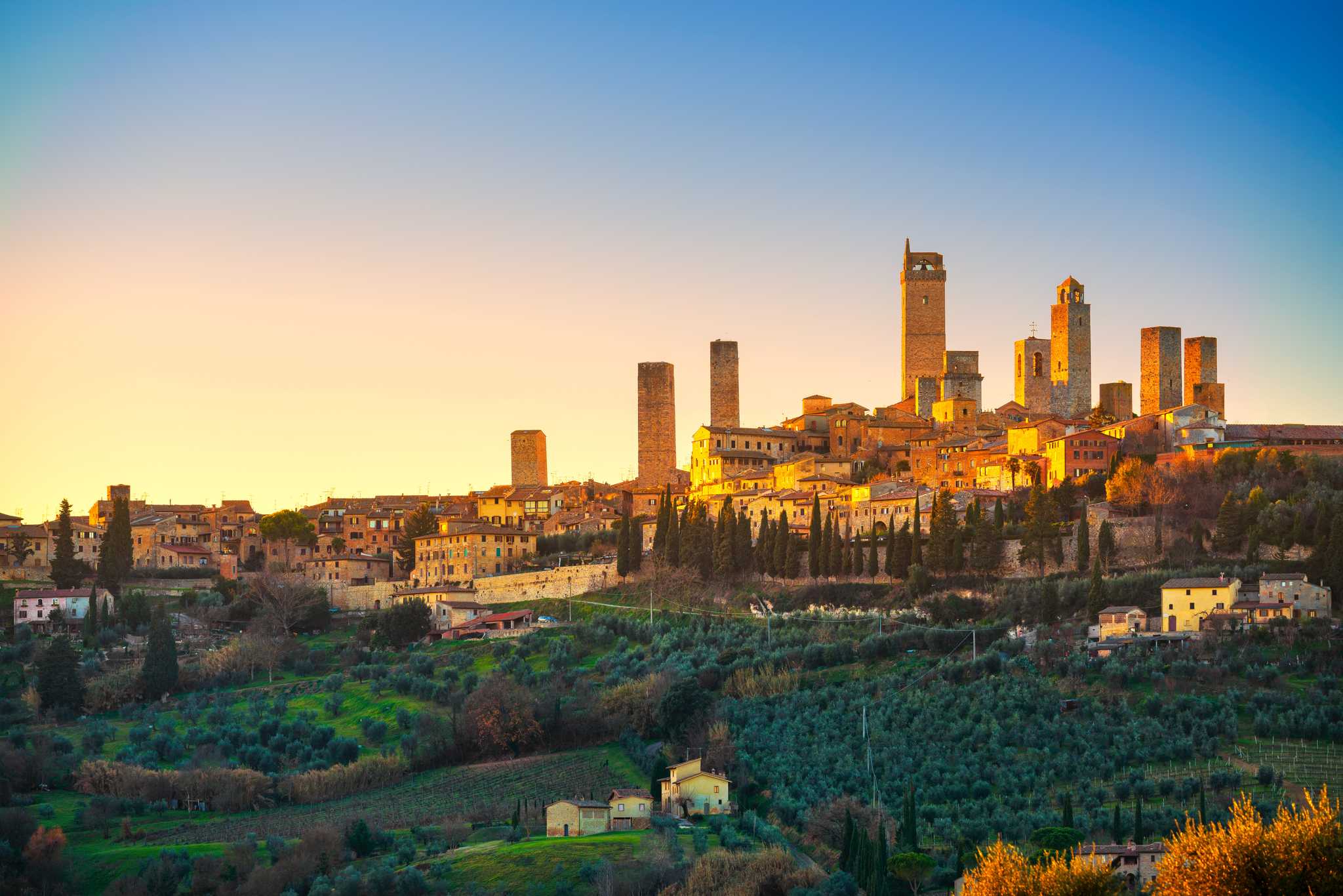 San Gimignano as seen from afar during sunset, with towers rising up in the background.
