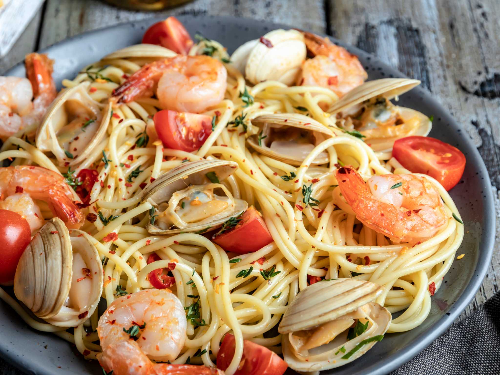 A close-up of seafood spaghetti served on a rustic wooden table.