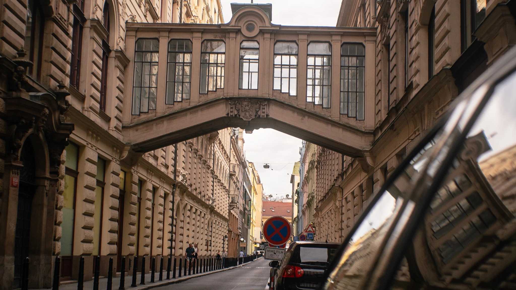 A private car on a street in Prague's old town, under an ornate covered bridge between two buildings