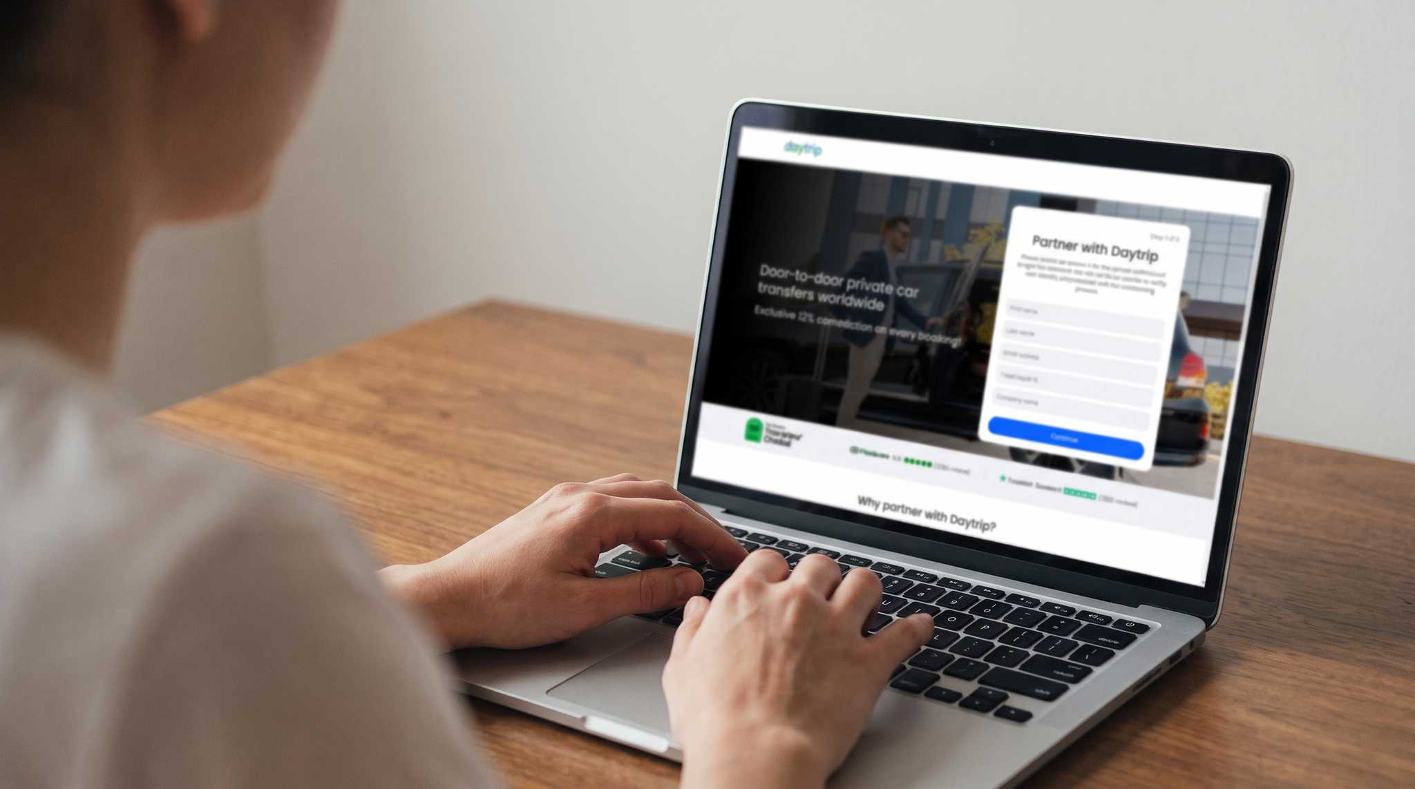A person typing on a laptop with the Daytrip Partner with Daytrip sign-up form open on screen