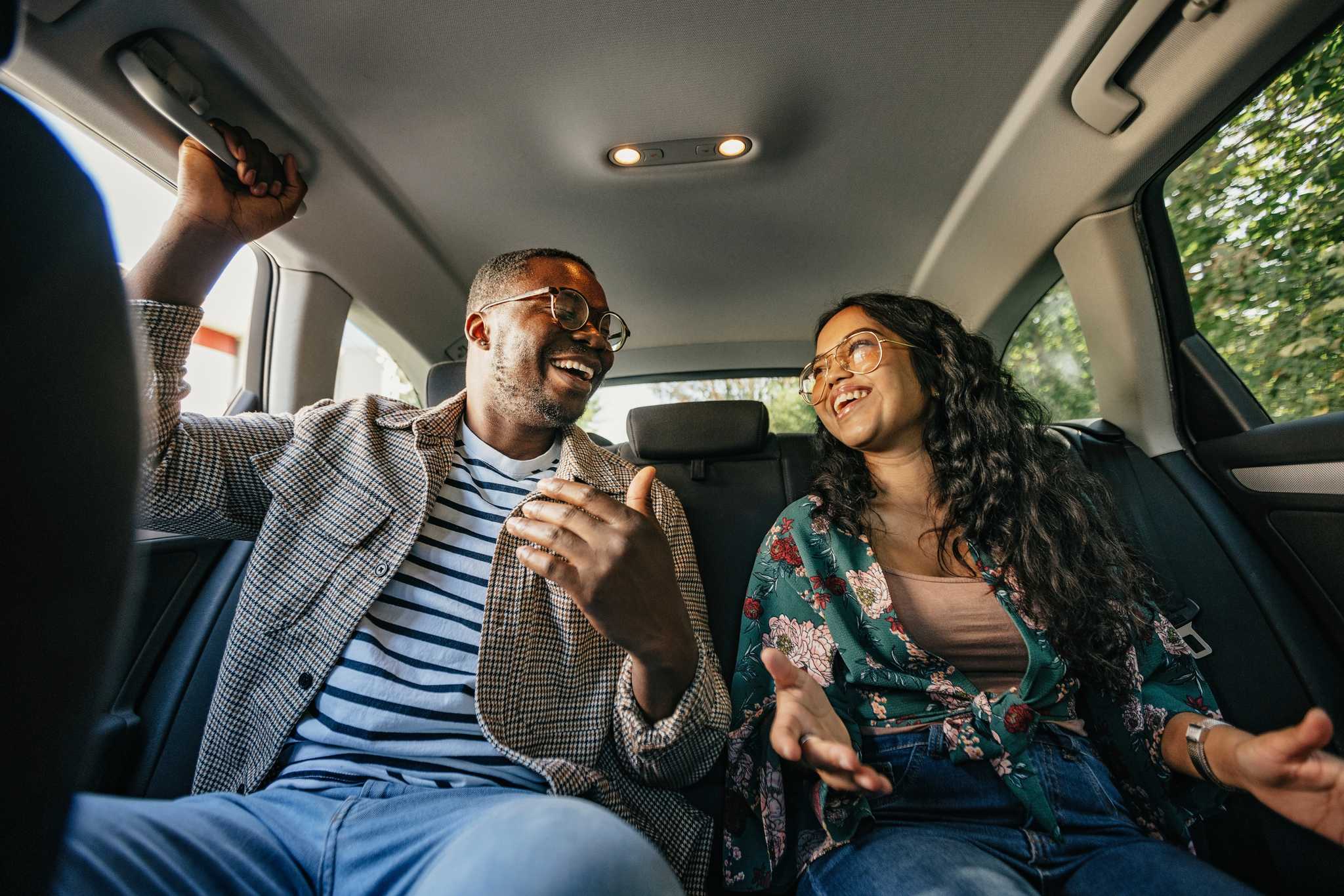 Two travelers laughing together in the back seat of a private car transfer