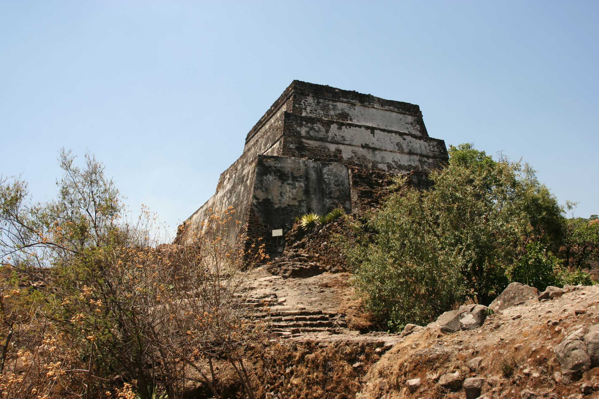 Tepoztlan’s ancient Aztec temple ruins surrounded by desert brush on a clear day.