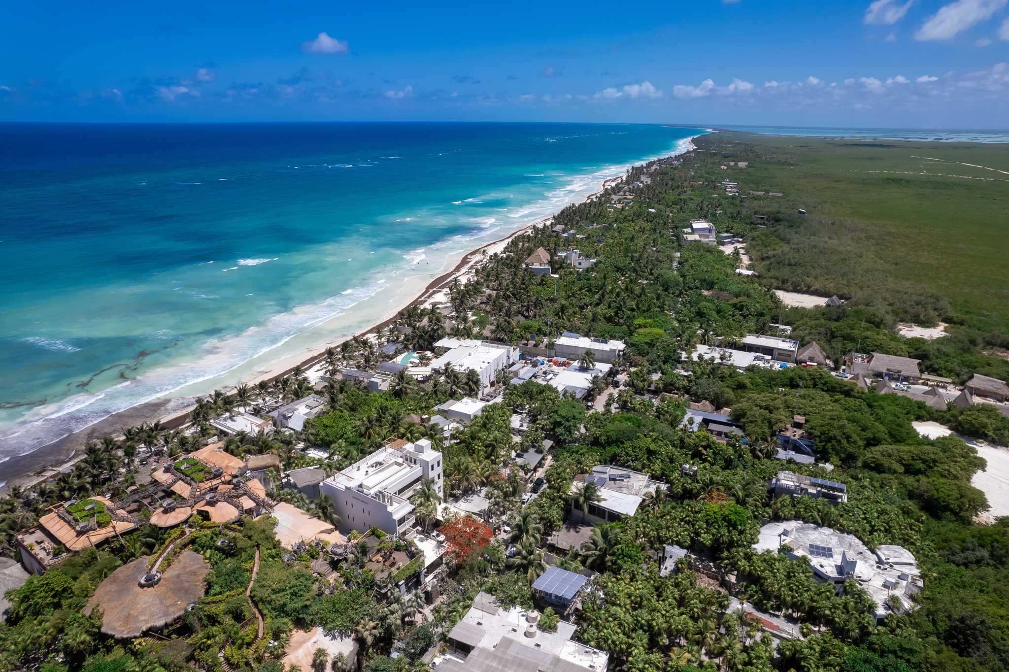 A small resort town emerges from the tropical forest on the Caribbean Sea.