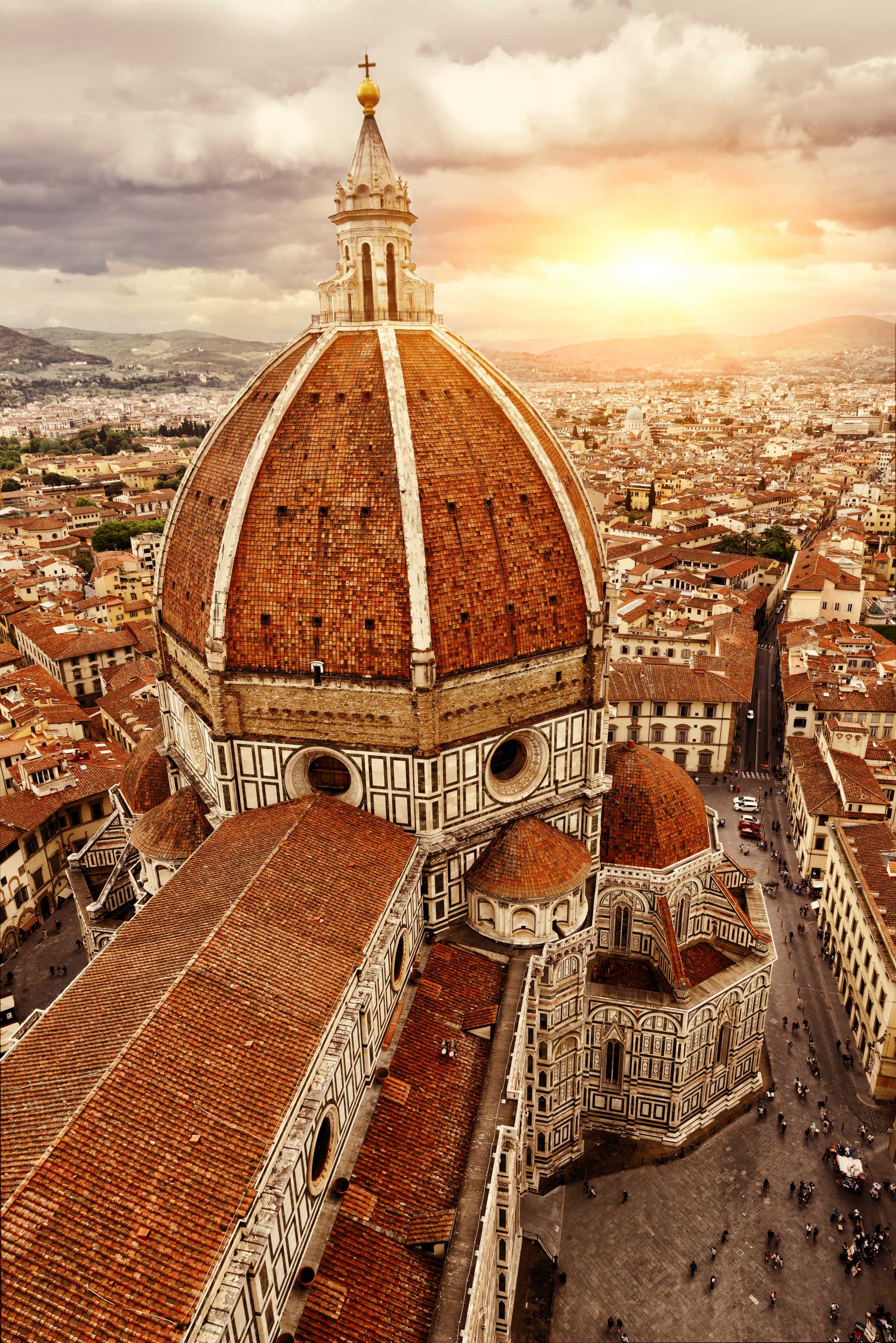 Florence’s red-domed duomo under a cloudy sunset, other red-roofed buildings in the distance.