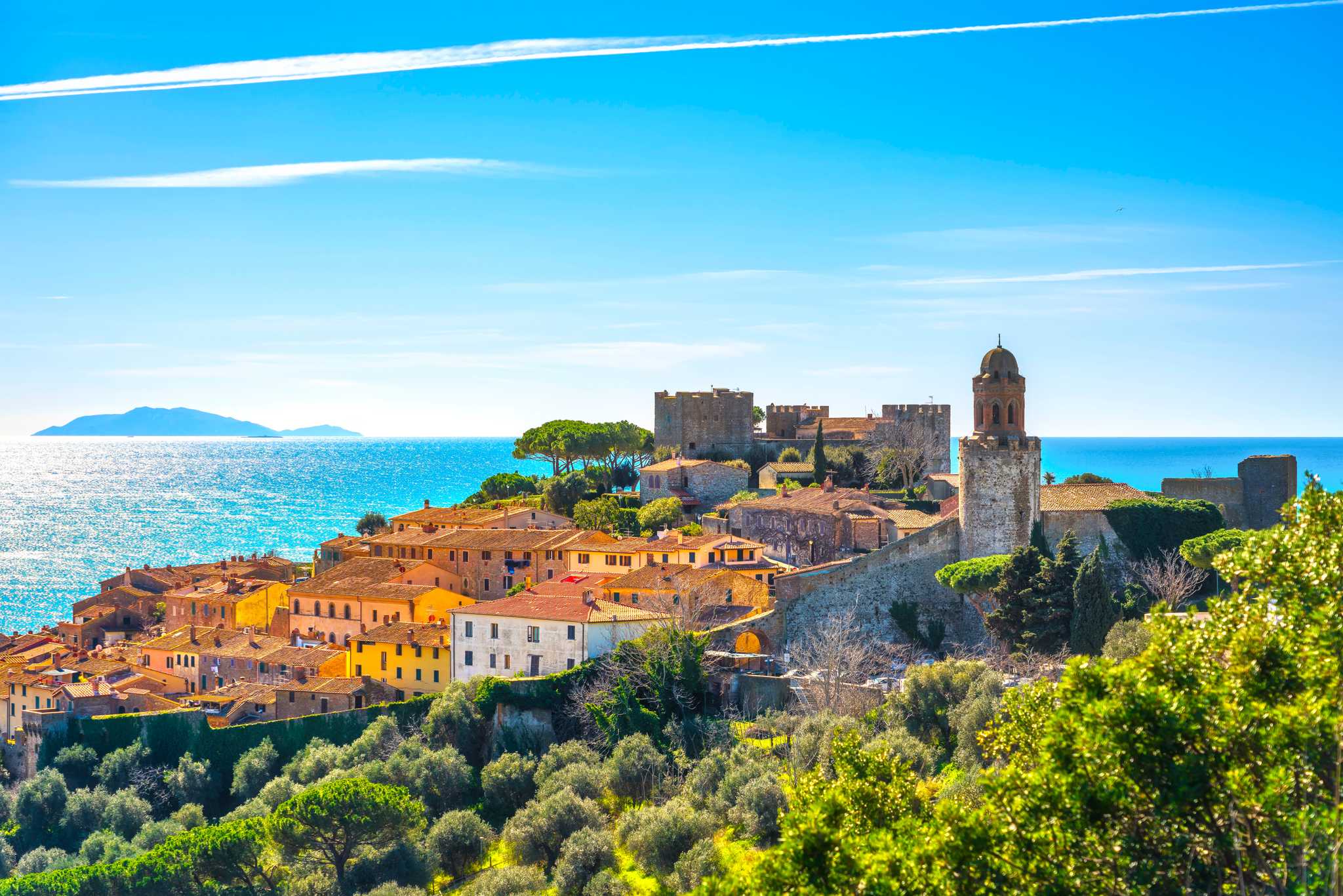Tuscan coastline with old buildings and a sunny sky.