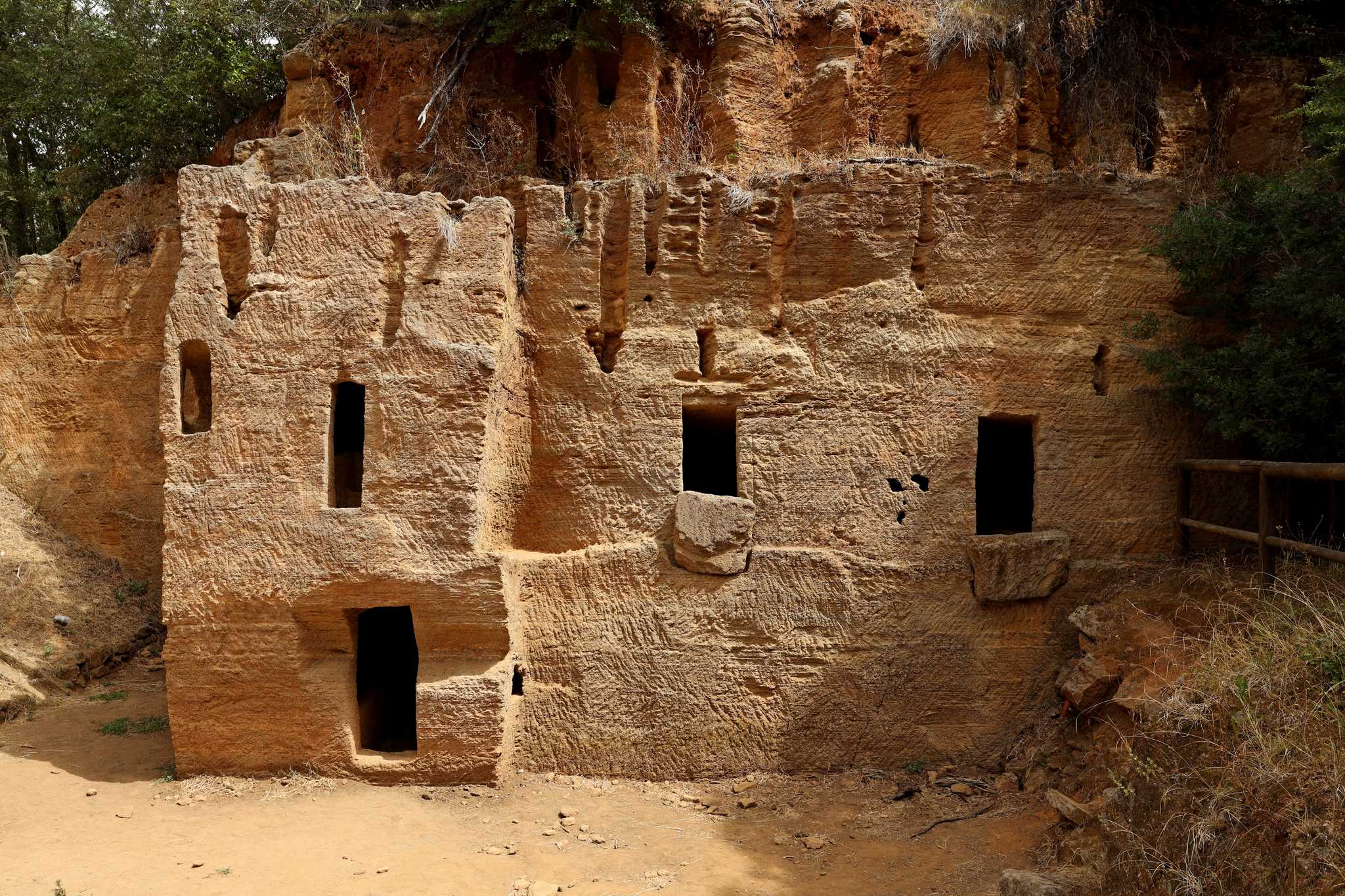 Etruscan necropolis, an ancient ruin, with rudimentary stone walls and window openings cut into the facade.