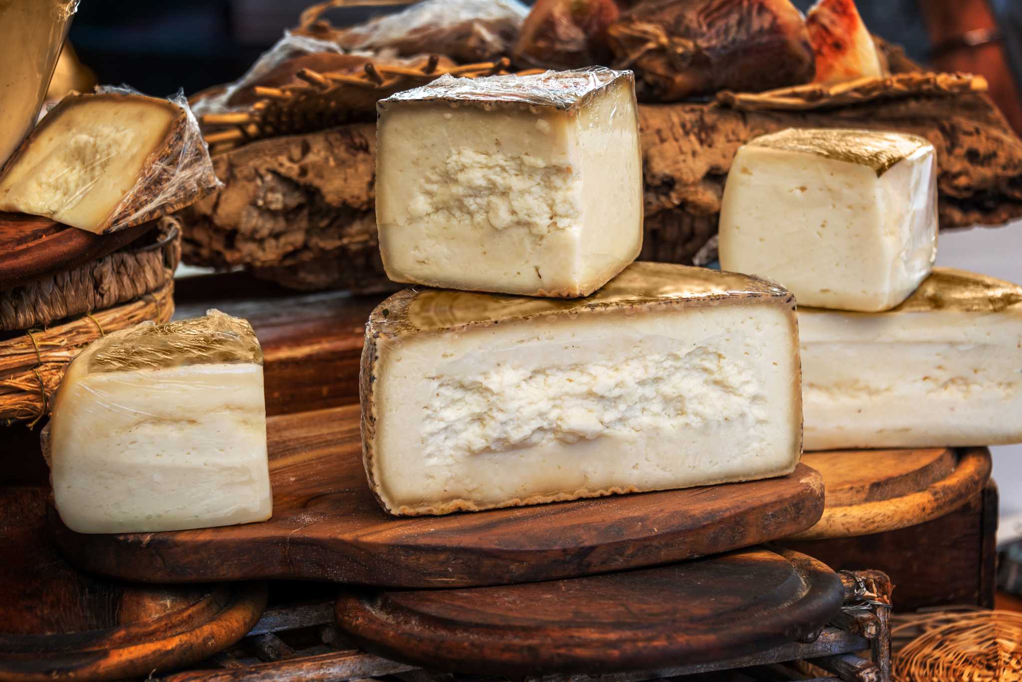 Cross-sections of Pecorino cheese stacked on a wooden cutting board.