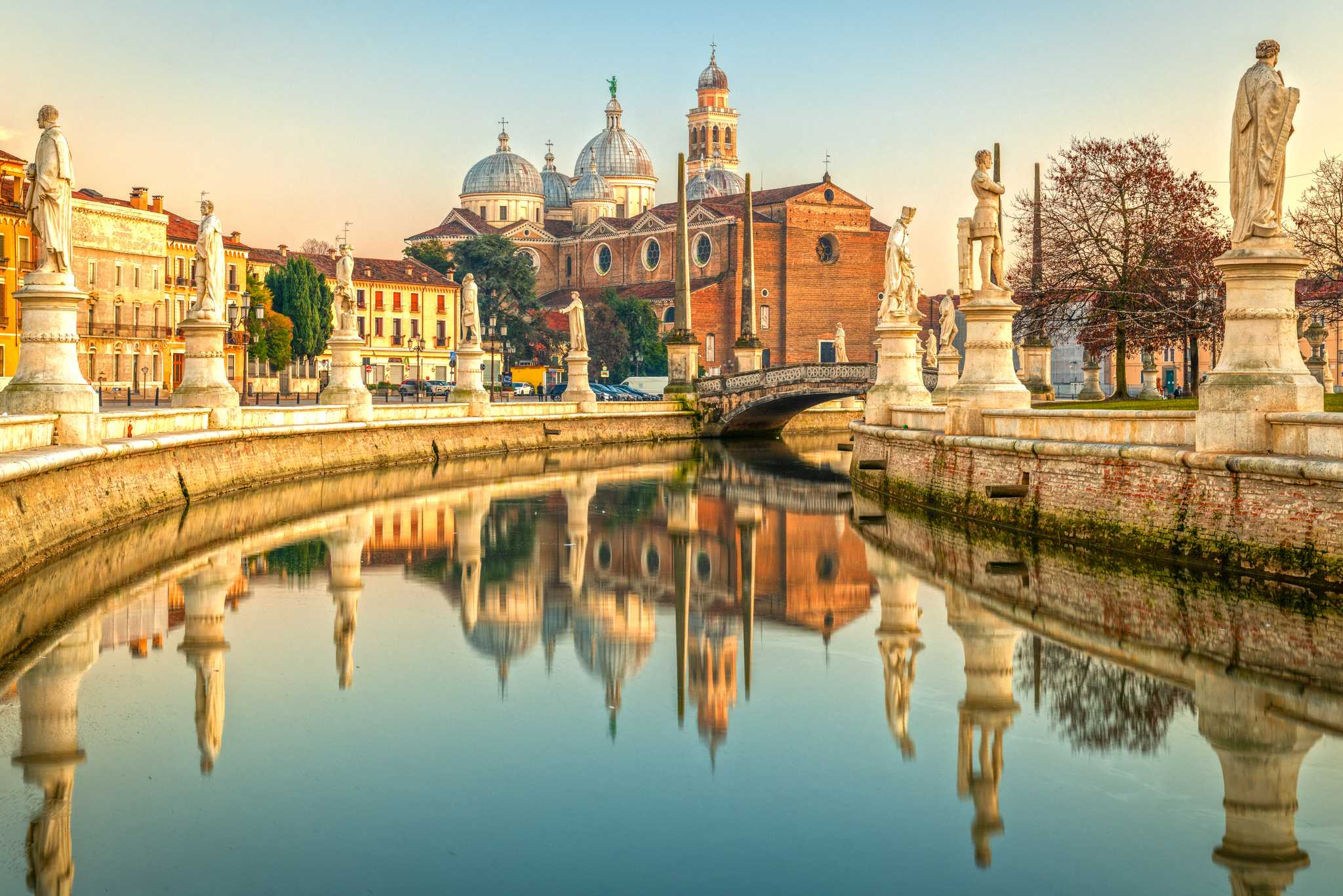 The canal in Padua, with wide promenades and white statues on either side, and The Basilica of St. Anthony.