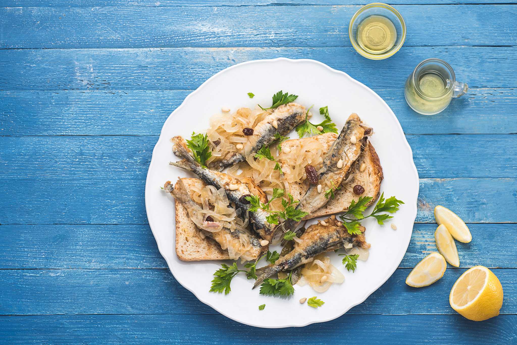 Venetian sarde in saor, sardines with onions and pine nuts on toast, served with lemon wedges.